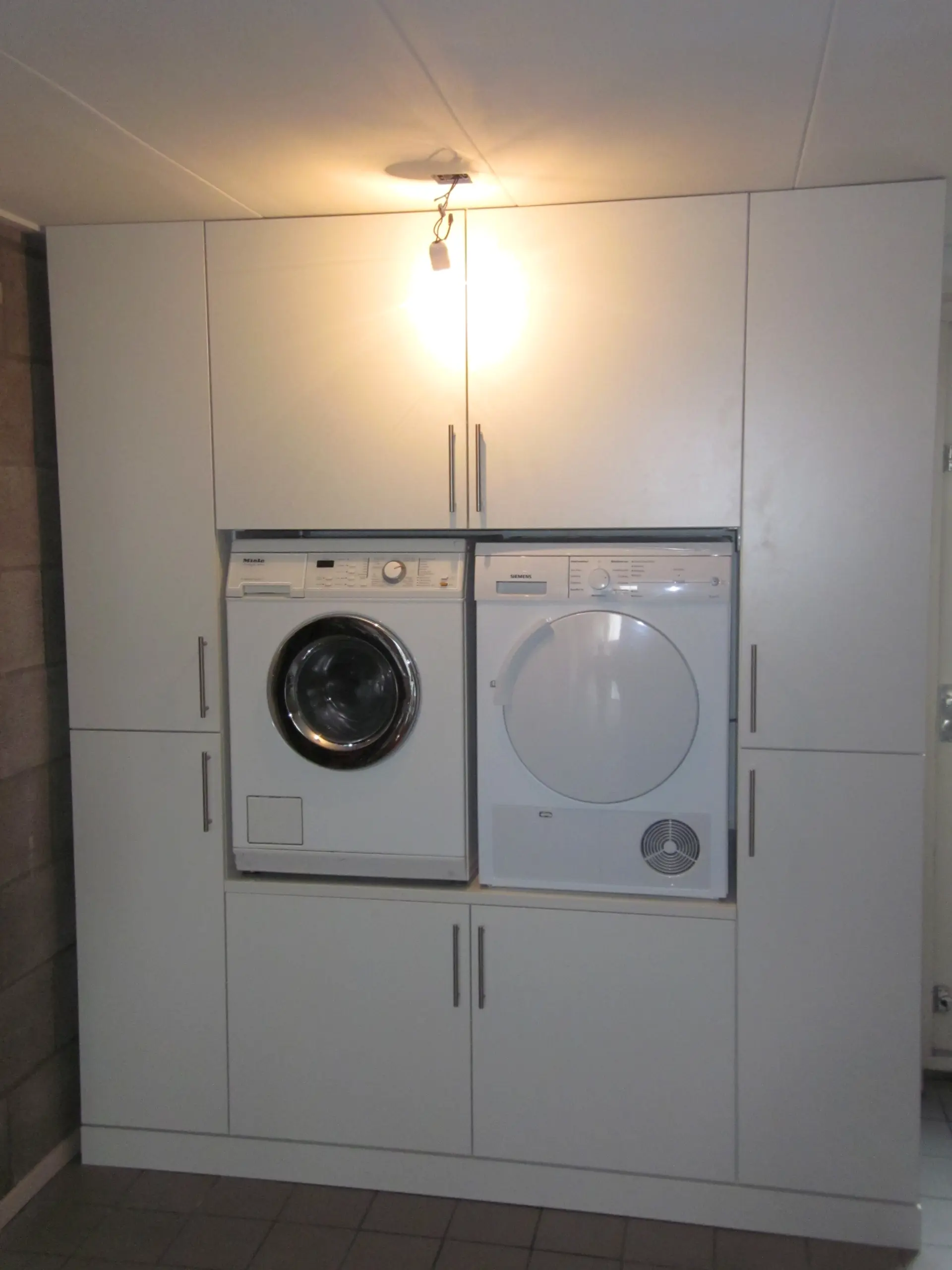 Bijkeuken met draaideuren en ingebouwde wasmachine en droger